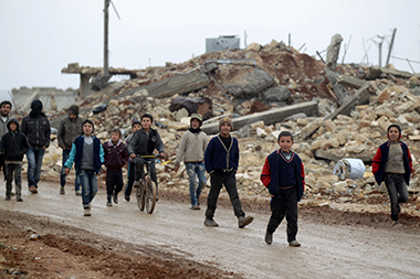 Un gruppo di giovani e bambini cammina per le strade di Doudyan, a nord di Aleppo