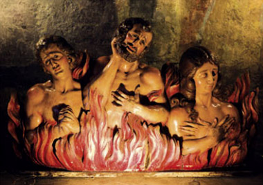Una scultura di legno che rappresenta tre anime condannate a bruciare all'inferno